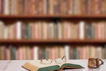 Books backgrounds. Closeup of an antique book with reading glasses on it and a brown clay mug on a...