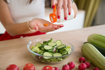 healthy lifestyle. Supporting immune system. woman takes vitamins. vitamin supplements for beauty, skin, hair, with green vegan food. at lunch at home