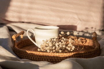 Obraz na płótnie Canvas Cup of coffee with milk on the bed with grey linen bed sheet. Morning coffee concept. Sunday loneliness relaxing, hygge mood. Minimalism composition with pastel neutral colors. Light and shadow.