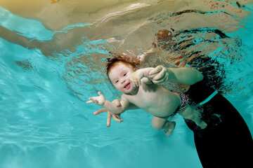 A child with Down syndrome is engaged in water sports and swims with his mother underwater in a children's pool with blue water. Children's disability. Concept. Portrait. Horizontal orientation.