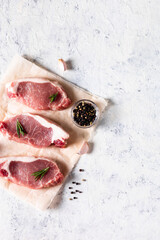 A pieces of raw fresh pork with rosemary and garlic on a vax paper on white background. Meat with spices