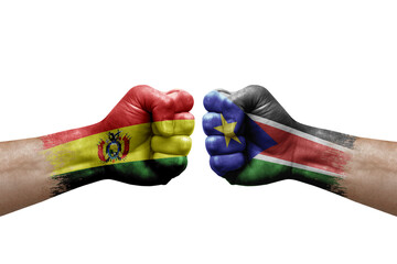 Two hands punch to each others on white background. Country flags painted fists, conflict crisis concept between bolivia and south sudan