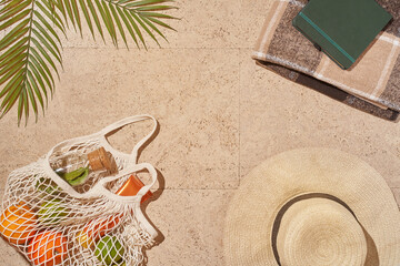 Summer sunny beach concept flat lay.Hat, string bag with fruits and lemonade, palm leaves and...