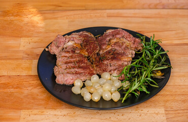 Sliced medium rare grilled Beef steak Ribeye with grilled onions  on plate on wooden background