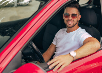 Fototapeta na wymiar A cheerful handsome man with sunglasses sitting inside his car looking at the camera.