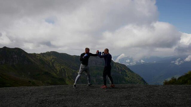 two men are boxing against the background of mountains. the camera is moving. the general plan