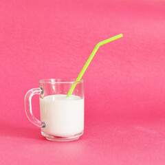 a cup with milk and a straw on a pink background