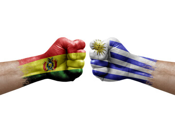 Two hands punch to each others on white background. Country flags painted fists, conflict crisis concept between bolivia and uruguay