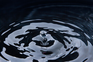 Blur Water droplets falling against the surface of the water create a beautiful ripple on the gray...