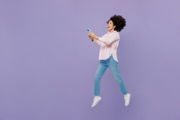 Full body side view young woman of African American ethnicity 20s wear pink striped shirt jump high...