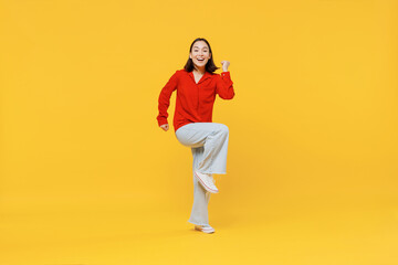 Fototapeta na wymiar Full size body length vivid young woman of Asian ethnicity 20s years old in casual clothes doing winner gesture celebrate clenching fists say yes isolated on plain yellow background studio portrait.