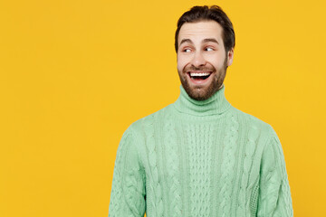 Young surprised amazed fun cool happy man 20s wearing mint knitted sweater look aside on workspace area mock up isolated on plain yellow background studio portrait. People lifestyle fashion concept.