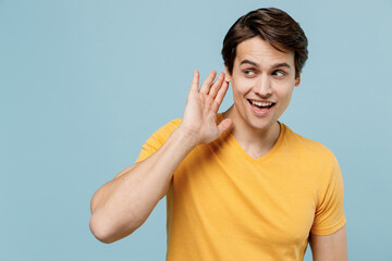 Young curious nosy smiling man 20s wear yellow t-shirt try to hear you overhear listening intently...