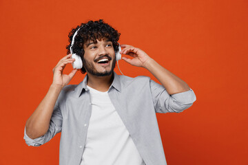 Cheerful exultant happy young bearded Indian man 20s years old wears blue shirt listen music in...