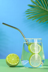 Homemade lemonade on green-blue background with palm leaves and lemon
