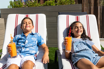 Two kids drinking orange juice on a hammocks