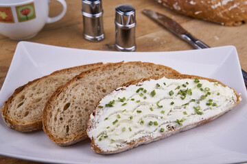Sesam-Dinkelkruste-Brot mit Frischkäse & Schnittlauch auf weißem Teller
