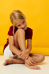 Obraz premium little girl sitting on the floor yellow background emotions