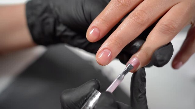 Hardware manicure in a beauty salon, female hands applying gel polish, covering the nail plate, woman's nails for beauty