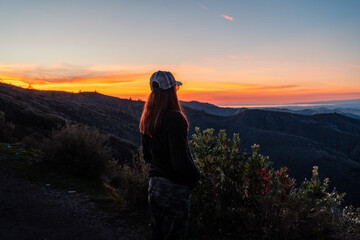 Fototapeta premium Sunset Over Mountains with Woman Looking Away