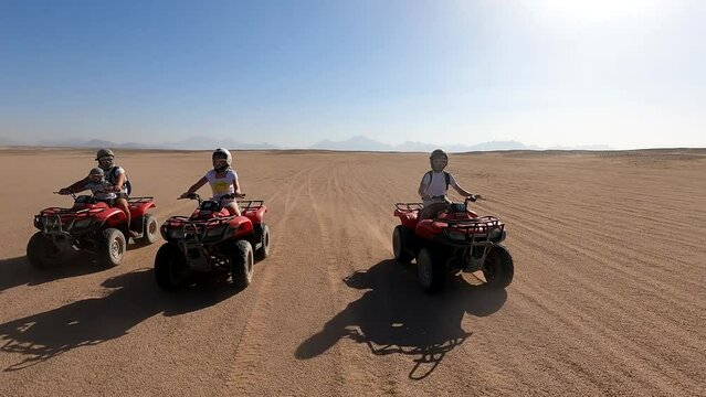 A family rides quad bikes in the desert. Quad bike tour in the desert