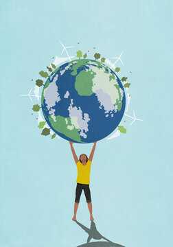 Determined, ambitious woman holding globe with wind turbines and green trees overhead

