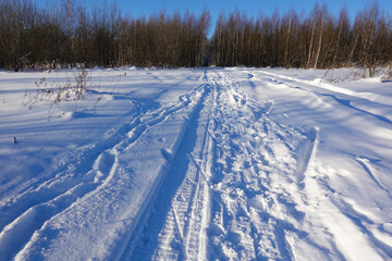 Winter road covered with snow with traces of skis and snowmobiles.