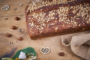 Schwarzbrot mit Haseln&uuml;ssen ungeschnitten mit Handtuch auf Holzbrett 