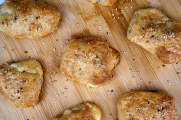 Knackiges Käsegebäck mit Sesam als kleine Brötchen auf Holzbrett