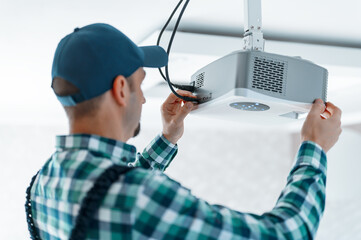 The specialist independently connects a multimedia video projector for home theater or presentations mounted on a ceiling bracket.
