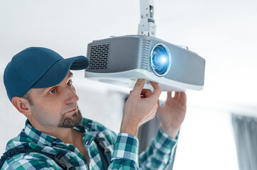 A specialist adjusts the focus of a multimedia video projector for home theater or presentations...