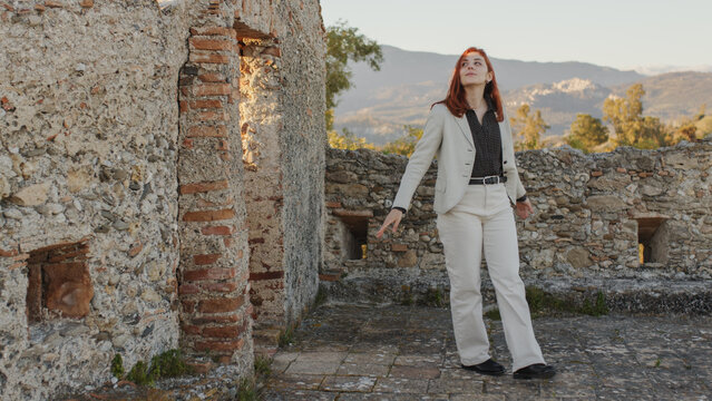 Beautiful girl with white dress explores an ancient Italian castle at sunset