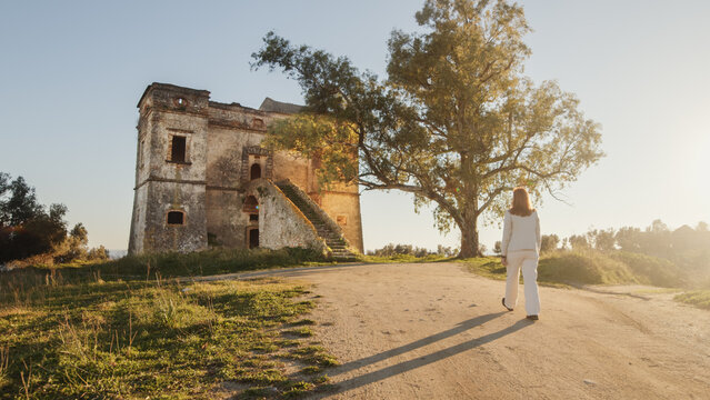 Beautiful girl in white dress enters an ancient castle in the countryside 