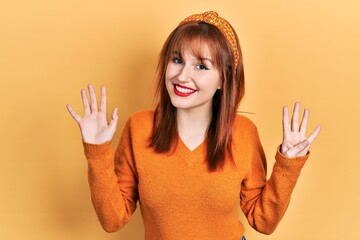 Redhead young woman wearing casual orange sweater showing and pointing up with fingers number nine...