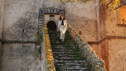 Beautiful girl with white dress comes down the entrance staircase of a castle