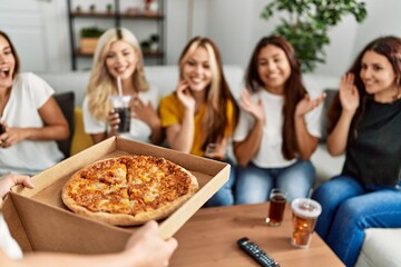 Group of young friends woman surprise for italian pizza sitting on the sofa at home.