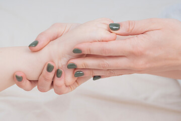 Baby's small legs in mom's hands, close-up. The concept of family happiness, loving parents. Baby care, massage. Background for Mother's day, baby's day. Touching mother and child