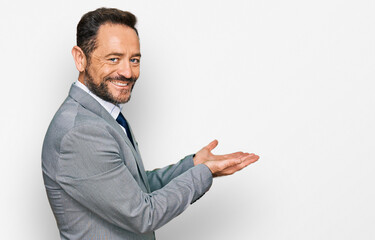 Middle age man wearing business clothes pointing aside with hands open palms showing copy space, presenting advertisement smiling excited happy