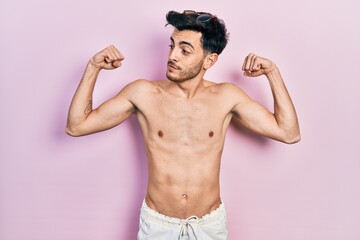 Fototapeta premium Young hispanic man wearing swimwear shirtless showing arms muscles smiling proud. fitness concept.
