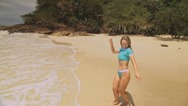 Crazy funny mother with daughter dancing on shallow water sea. Happy woman with her girl child enjoying her vacation on tropical island. Smiling girls jump on the sand. Concept family summer holidays