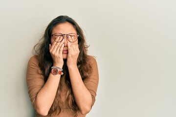 Young hispanic girl wearing casual clothes and glasses rubbing eyes for fatigue and headache,...