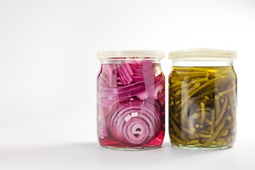 Pickled red onion and garlic arrows in glass jars on white background. Fermented vegetables.