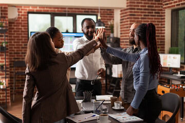 Happy excited businessteam rising hands celebrating business achievement winning management partnership enjoying successful collaboration in startup office. Diverse businesspeople at workplace