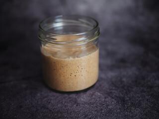 Homemade bread sourdough in a glass jar on a dark background.