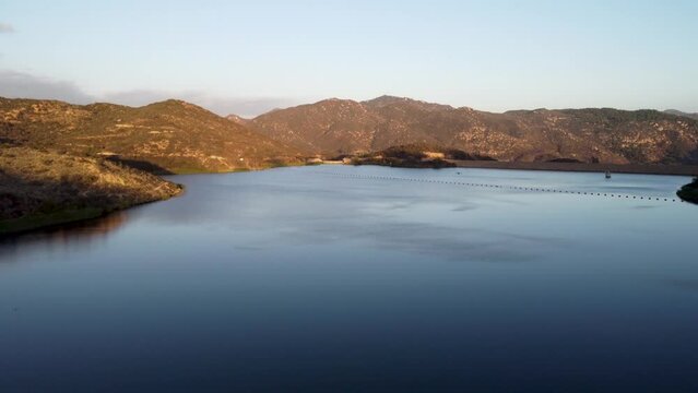 A beautiful aerial reveal shot with a drone flying over Dixon Lake towards a dam in Escondido, California