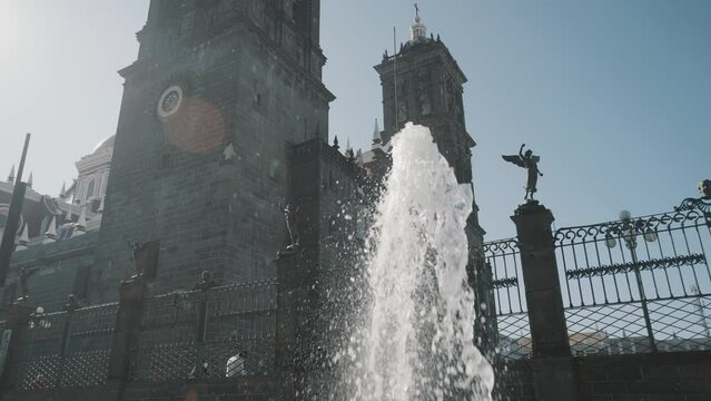 Close up shot of spraying fountain in front of historic Puebla Cathedral and sunlight at summer day,Mexico - Slow motion shot