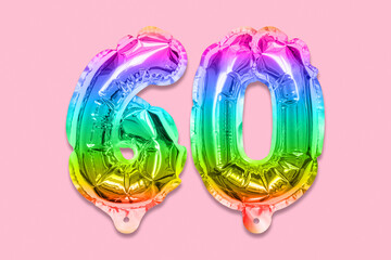 Rainbow foil balloon number, digit sixty on a pink background. Birthday greeting card with inscription 60. Anniversary concept. Top view. Numerical digit. Celebration event, template.