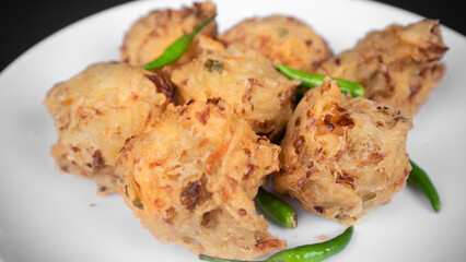 close up a plate of vegetable fritters in a black background