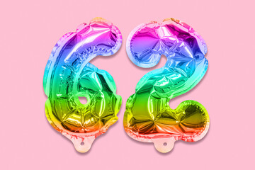 Rainbow foil balloon number, digit sixty two on a pink background. Birthday greeting card with inscription 62. Anniversary concept. Top view. Numerical digit. Celebration event, template.