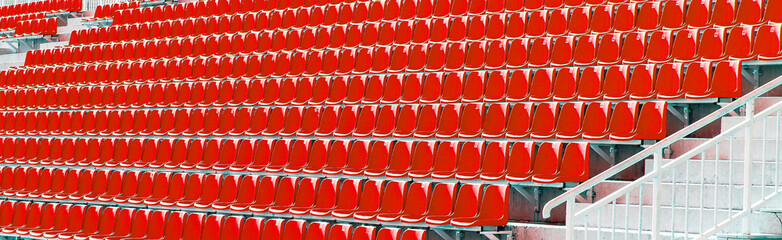 Folded red plastic chairs on a temporary tribune. Selective focus